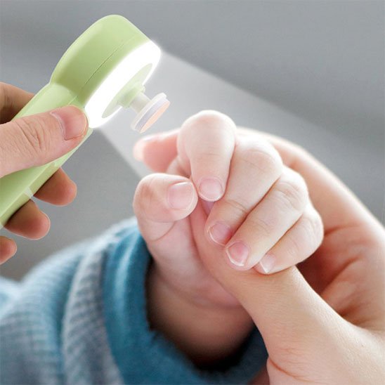 Mains d'une maman utilisant La LumiOngles™ avec sa lumière LED sur les petits ongles d'un bébé, l'une tenant l'appareil et l'autre la main de l'enfant. L'image évoque la tranquillité et la sécurité durant le soin.