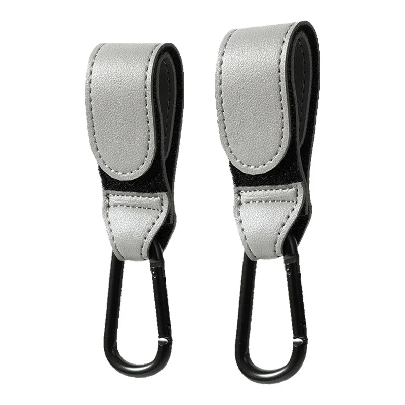 Photo des crochets Fix'Poussette™ BesoinBébé™ en couleur grise. Mousquetons universels en aluminium, accessoires pour poussette et landau, présentés sur fond neutre pour mettre en valeur leur design, finition et teinte élégante.